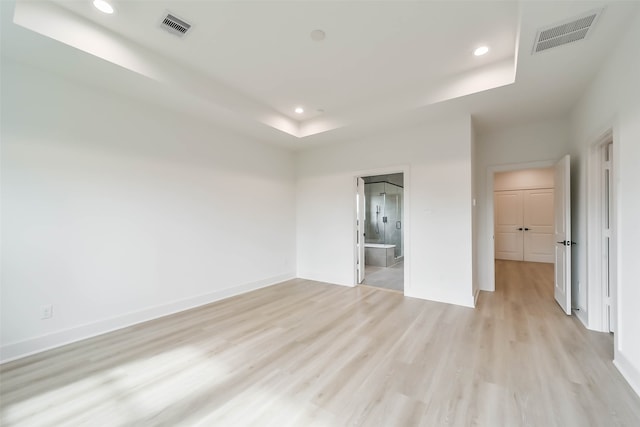 unfurnished room featuring a raised ceiling and light wood-type flooring