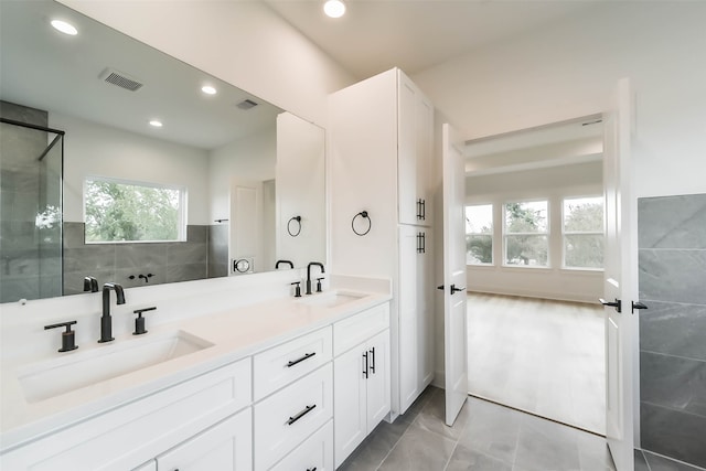 bathroom with a tile shower, vanity, and tile patterned floors