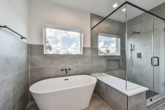 bathroom with independent shower and bath, tile patterned flooring, and tile walls