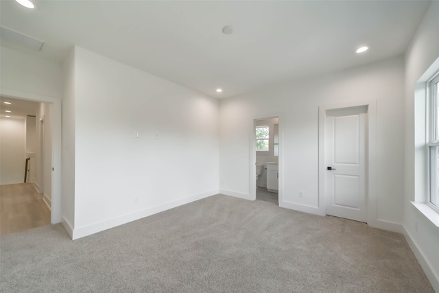 unfurnished bedroom with ensuite bath and light colored carpet