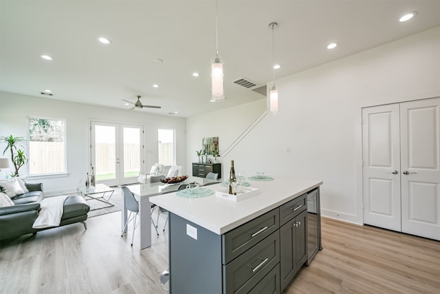 kitchen featuring light hardwood / wood-style floors, ceiling fan, decorative light fixtures, and an island with sink