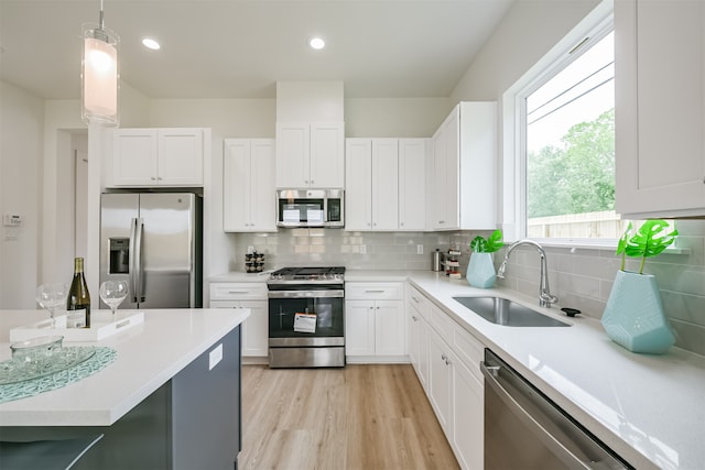 kitchen with hanging light fixtures, white cabinetry, sink, and appliances with stainless steel finishes