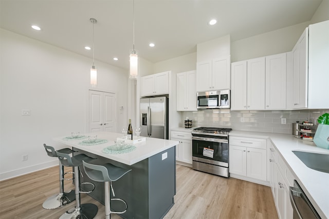 kitchen with white cabinetry, stainless steel appliances, light hardwood / wood-style floors, and a kitchen island