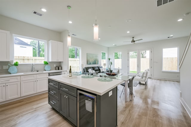 kitchen featuring light hardwood / wood-style floors, pendant lighting, sink, white cabinetry, and wine cooler