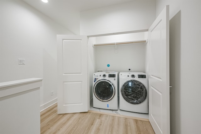 clothes washing area featuring separate washer and dryer and light hardwood / wood-style floors