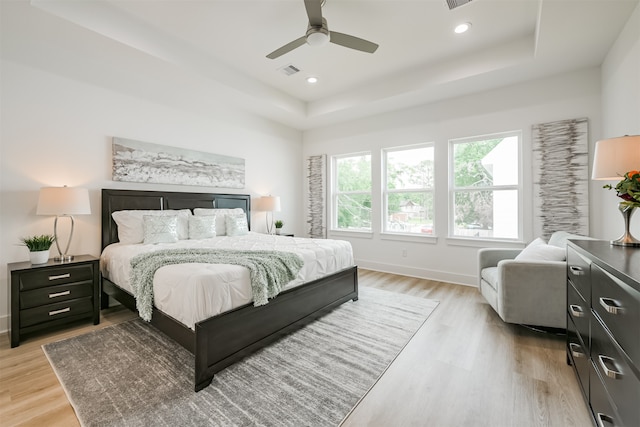 bedroom featuring ceiling fan, a tray ceiling, and light hardwood / wood-style floors