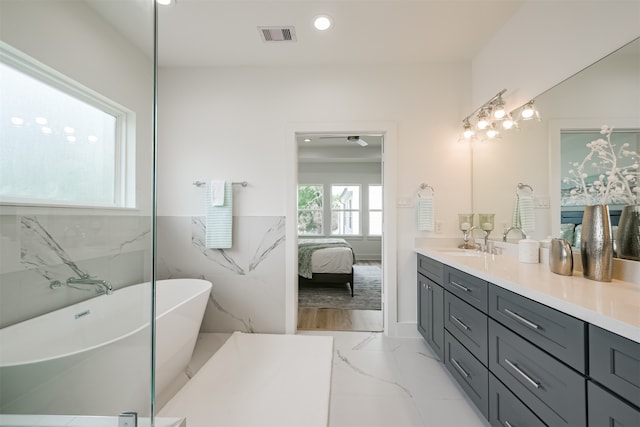 bathroom with a tub to relax in, vanity, and tile walls