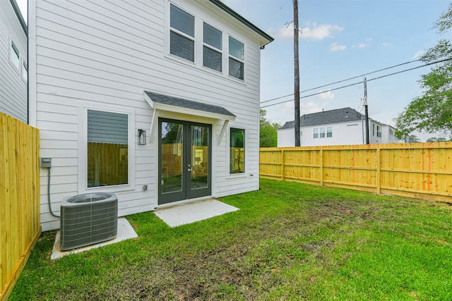 back of property with central AC unit and a yard