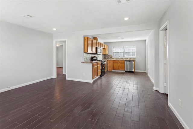 kitchen featuring a textured ceiling, backsplash, stainless steel appliances, and dark wood-type flooring