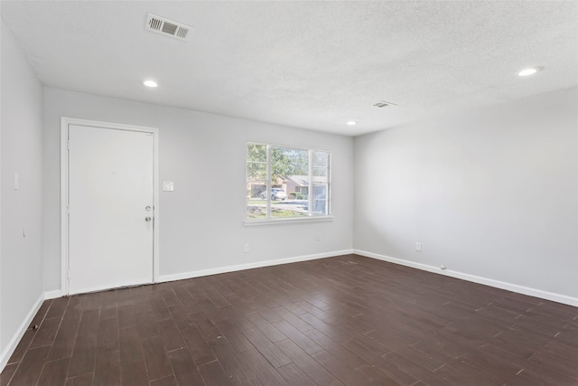 unfurnished room with a textured ceiling and dark wood-type flooring