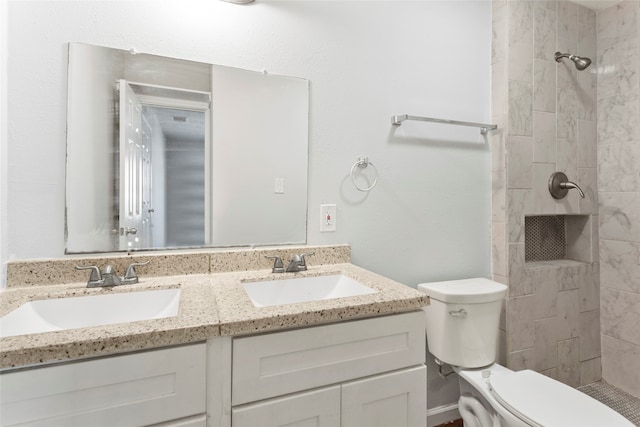 bathroom with tiled shower, vanity, and toilet