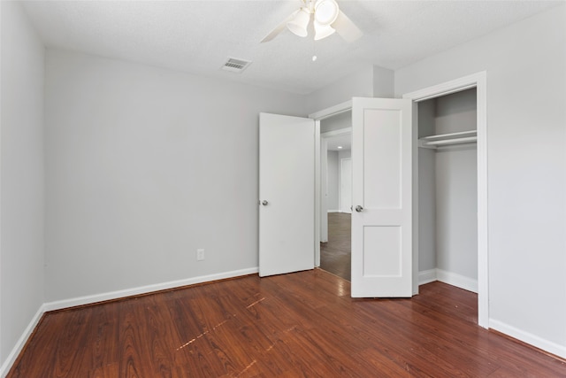 unfurnished bedroom featuring ceiling fan, dark hardwood / wood-style flooring, a textured ceiling, and a closet