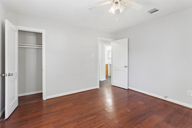 unfurnished bedroom featuring a closet, ceiling fan, dark hardwood / wood-style flooring, and a textured ceiling