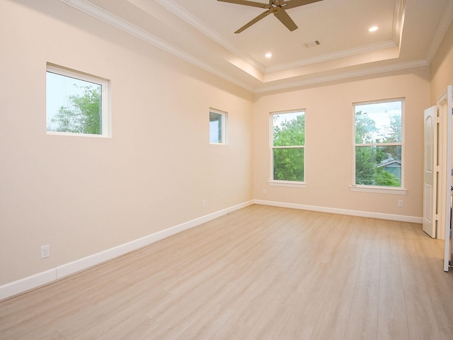 empty room featuring light hardwood / wood-style floors, a healthy amount of sunlight, ceiling fan, and a tray ceiling