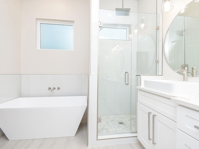 bathroom featuring plus walk in shower, vanity, and a healthy amount of sunlight