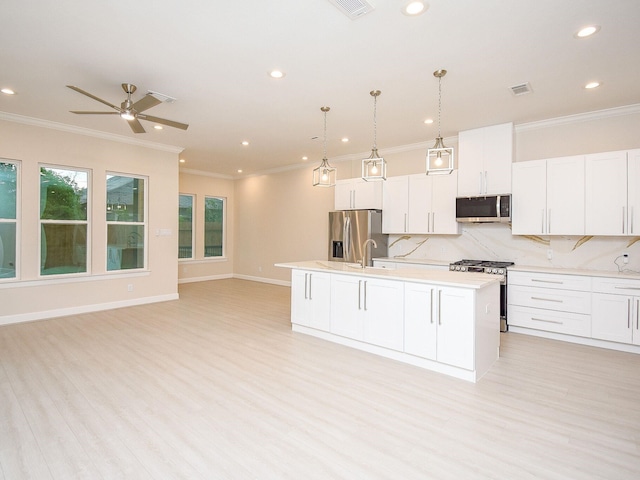 kitchen with a center island with sink, white cabinets, hanging light fixtures, light wood-type flooring, and appliances with stainless steel finishes