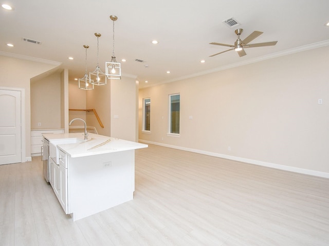 kitchen featuring a kitchen island with sink, ornamental molding, white cabinetry, hanging light fixtures, and light hardwood / wood-style flooring