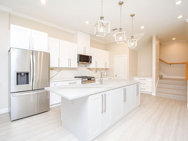 kitchen with pendant lighting, appliances with stainless steel finishes, an island with sink, and white cabinets