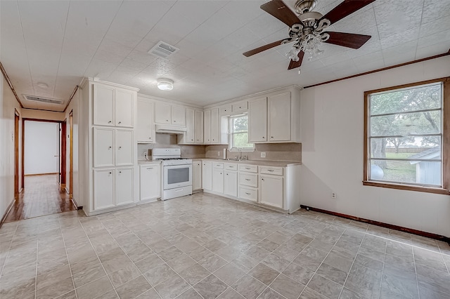 kitchen featuring white gas range, sink, ornamental molding, ceiling fan, and white cabinets