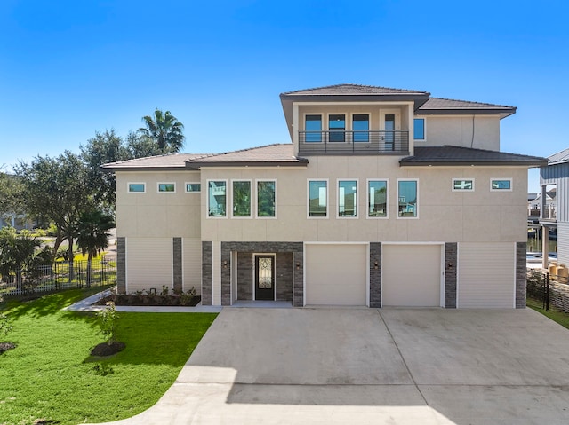 view of front facade with a balcony, a garage, and a front lawn