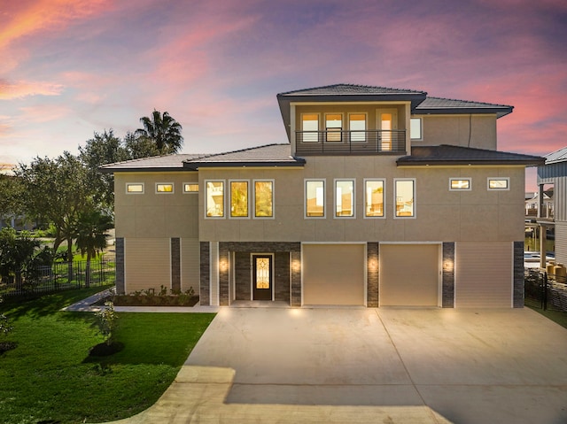 view of front of home featuring driveway, a balcony, an attached garage, fence, and a front lawn