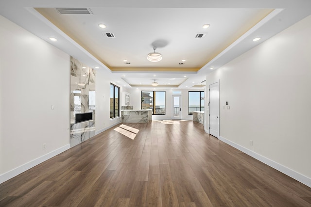 unfurnished living room with a tray ceiling and hardwood / wood-style flooring