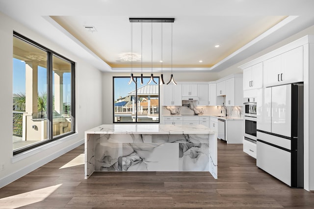 kitchen with a tray ceiling, a kitchen island, white refrigerator, and oven