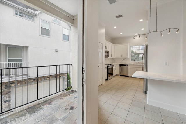 kitchen with backsplash, sink, light tile patterned floors, white cabinetry, and stainless steel appliances