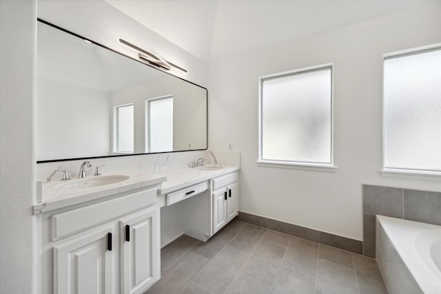 bathroom featuring a wealth of natural light, vanity, a relaxing tiled tub, and vaulted ceiling