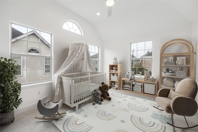 bedroom with carpet, vaulted ceiling, multiple windows, and a nursery area