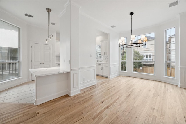 unfurnished dining area featuring a notable chandelier, light hardwood / wood-style floors, and ornamental molding