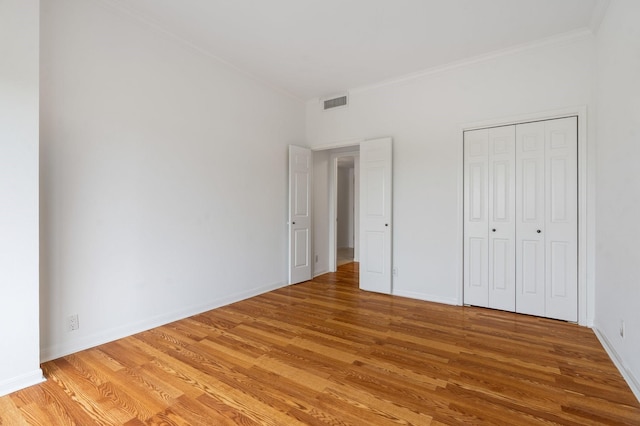 unfurnished bedroom with a closet, light wood-type flooring, and crown molding