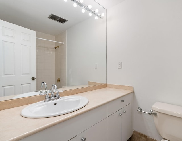 bathroom with vanity, toilet, and tiled shower