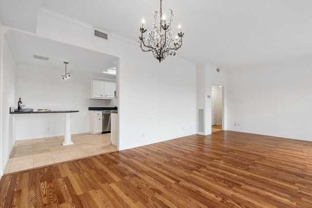 unfurnished living room with a notable chandelier, crown molding, and light hardwood / wood-style flooring