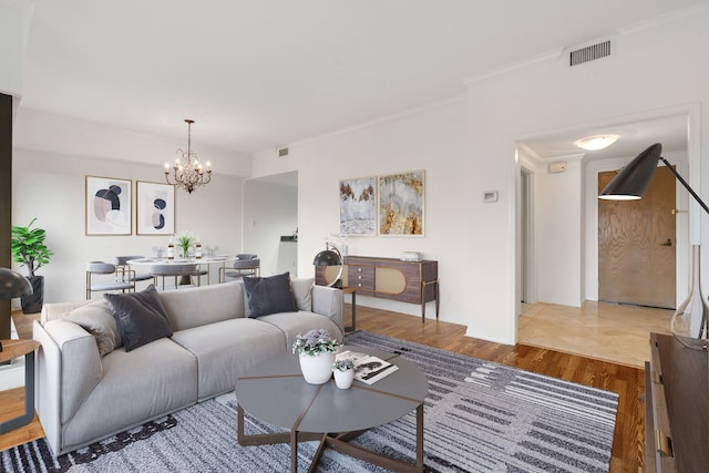 living room with a chandelier, hardwood / wood-style flooring, and ornamental molding