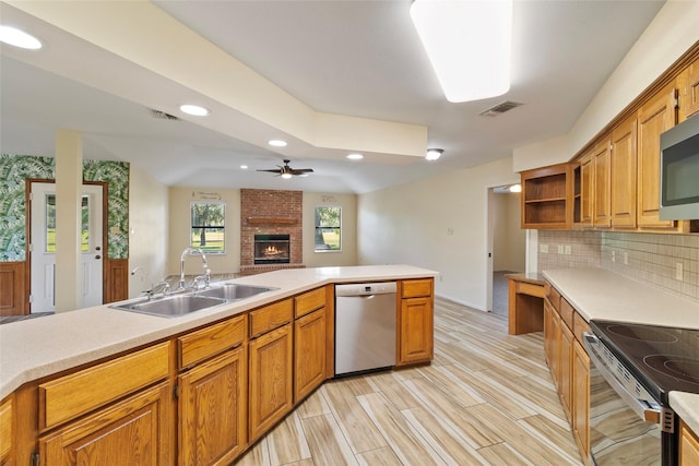 kitchen with ceiling fan, sink, backsplash, appliances with stainless steel finishes, and light wood-type flooring