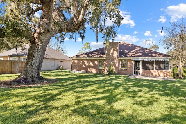 rear view of house with a yard and a sunroom