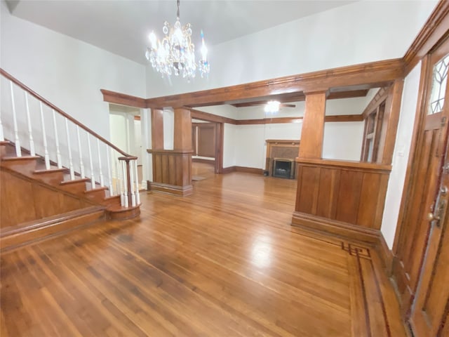 unfurnished living room with wood-type flooring, a notable chandelier, and a towering ceiling