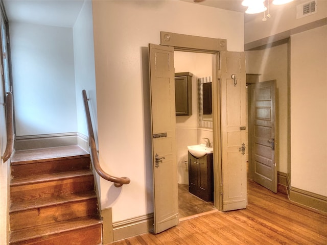 staircase with sink and hardwood / wood-style flooring