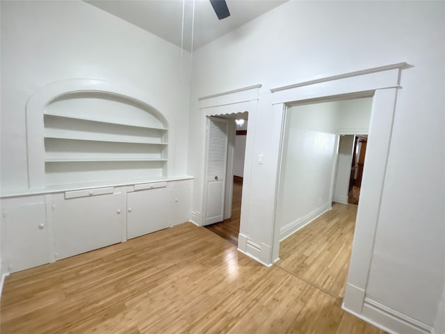 interior space featuring built in shelves, light hardwood / wood-style floors, and ceiling fan