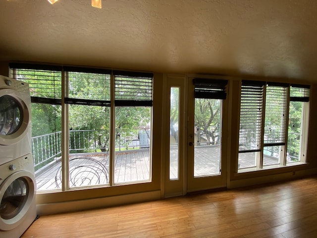 entryway with light wood-type flooring, a wealth of natural light, a textured ceiling, and stacked washer and clothes dryer