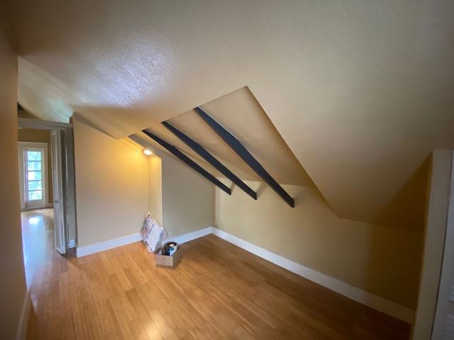 interior space with hardwood / wood-style floors and vaulted ceiling with beams