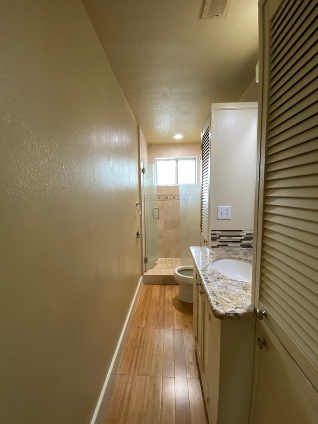 bathroom featuring vanity, hardwood / wood-style flooring, toilet, and a shower with door