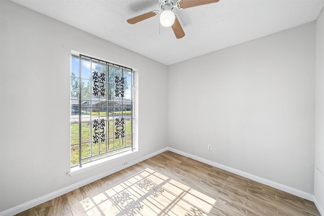 empty room with a textured ceiling, ceiling fan, and light hardwood / wood-style flooring