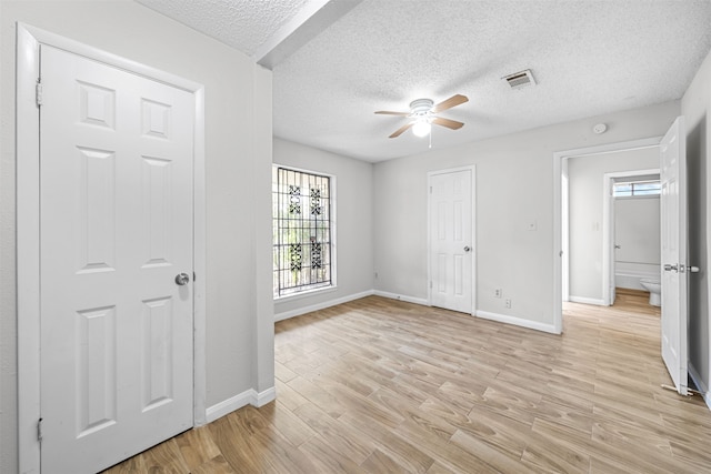 unfurnished bedroom featuring light hardwood / wood-style floors, ceiling fan, and a textured ceiling