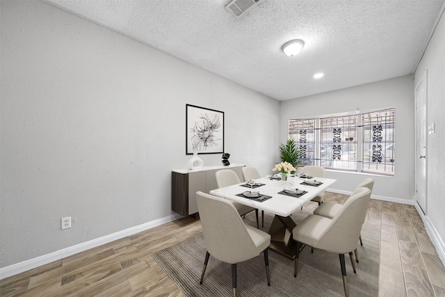 dining area featuring light wood-type flooring and a textured ceiling