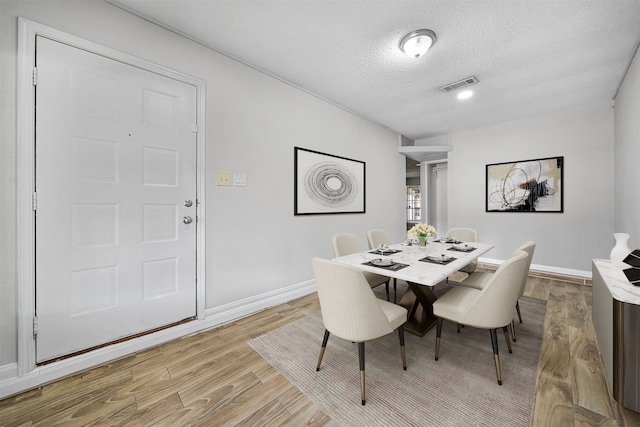 dining room with a textured ceiling and light wood-type flooring