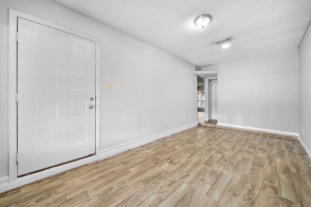 unfurnished room featuring a textured ceiling and light hardwood / wood-style flooring