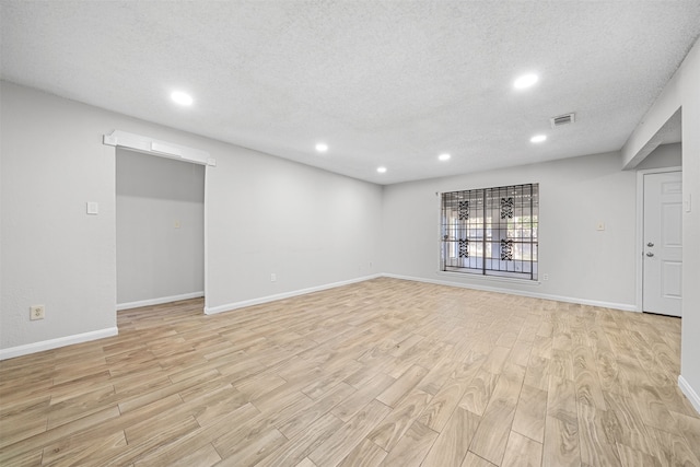 unfurnished room featuring a textured ceiling and light hardwood / wood-style flooring