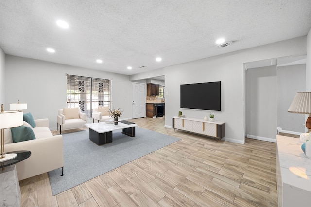 living room with a textured ceiling and light hardwood / wood-style flooring